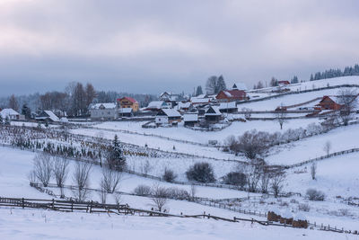 Houses on snow covered land against sky