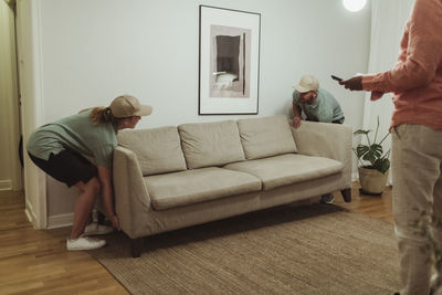 Male and female coworkers carrying sofa at customer's living room