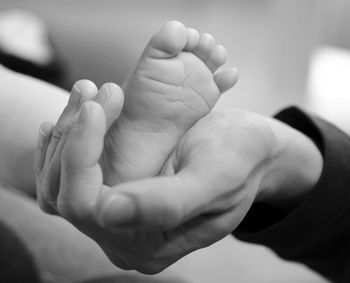 Cropped image of father hand holding baby foot