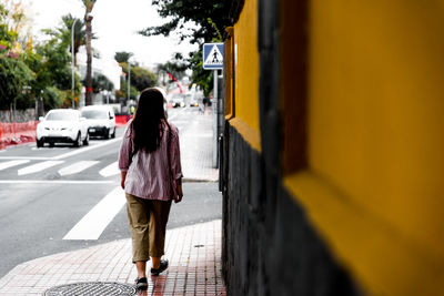 Rear view of woman walking on road