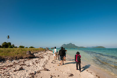 People on beach against clear blue sky