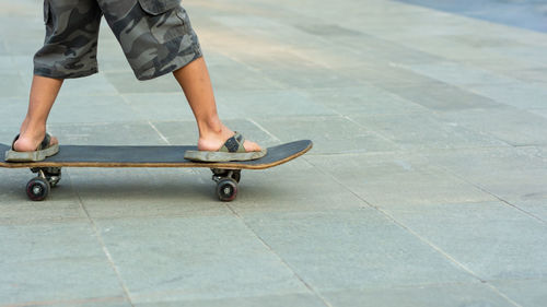 Low section of man skateboarding on footpath