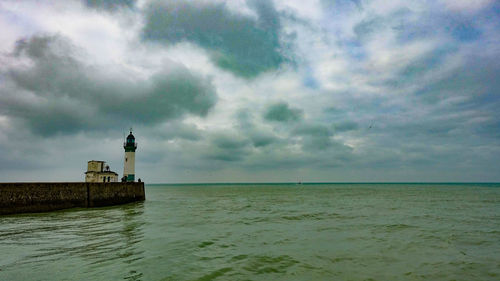 Lighthouse by sea against sky