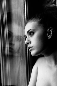 Close-up of woman looking through window at home