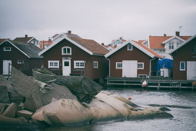 Houses by river in town against sky