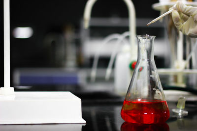 Close-up of red chemical in flask on table