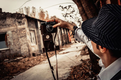 Close-up of man taking selfie with analog photo camera.