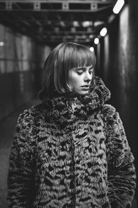 Beautiful young woman wearing fur coat standing in subway