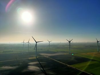 Wind turbines on field against sky