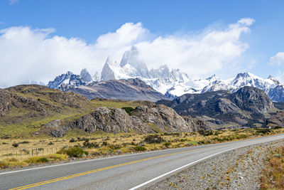 Road by snowcapped mountains against sky