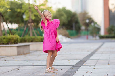 Portrait of young woman standing on footpath