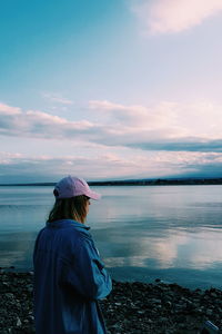 Rear view of woman standing by sea against sky