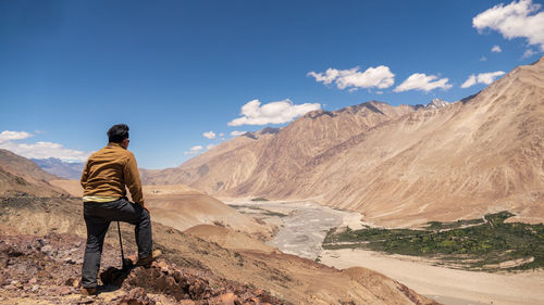 Rear view of man looking at mountains against sky