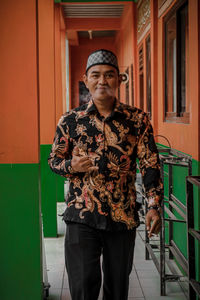 Portrait of young man standing against wall