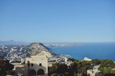 View of sea and cityscape against clear blue sky