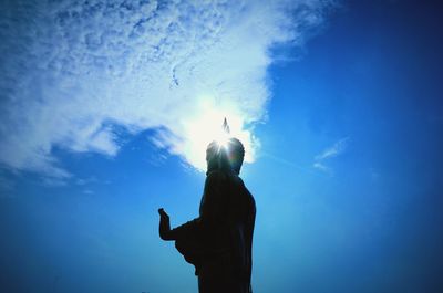 Rear view of woman standing against blue sky