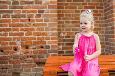 Portrait of girl standing against brick wall