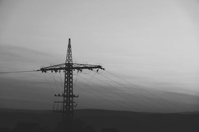 Low angle view of silhouette electricity pylon against sky