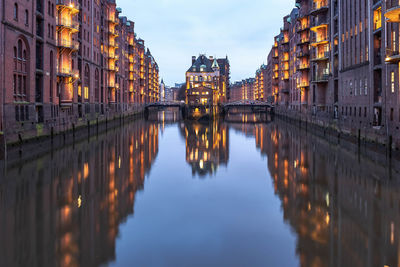 Reflection of buildings in canal against sky