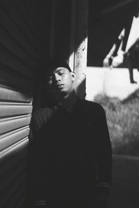 Young man with eyes closed standing by wall