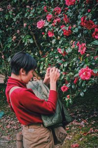 Full length of man standing by red flowering plants