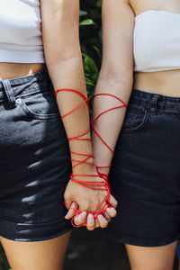 Two women with thread holding hands