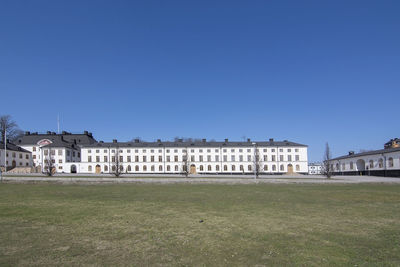 Buildings on field against clear blue sky