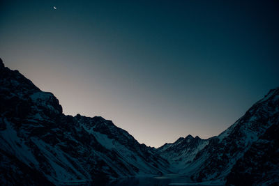 Low angle view of snowcapped mountains against clear blue sky