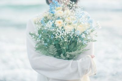 Close-up of woman holding bouquet of white flowering plant