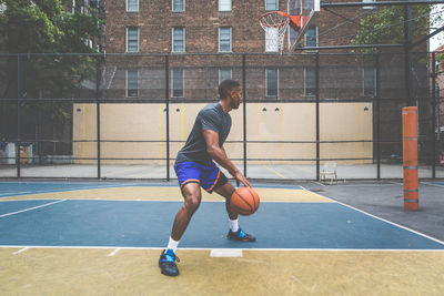 Young man practicing basketball in court