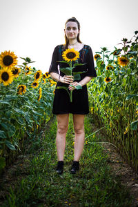 Full length portrait of young woman standing in field