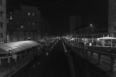 Illuminated street amidst buildings in city at night