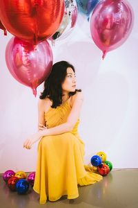 Young woman with balloons against white background