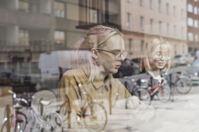 Young computer programmers sitting in office seen through glass window