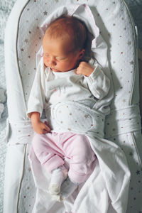 Gentle innocent newborn baby sleeps on light baby cocoon, closeup portrait at home