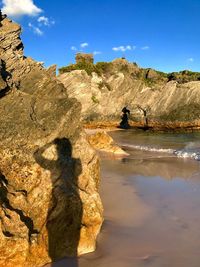 Shadow of rocks on shore against sky