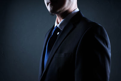Midsection of businessman standing against black background