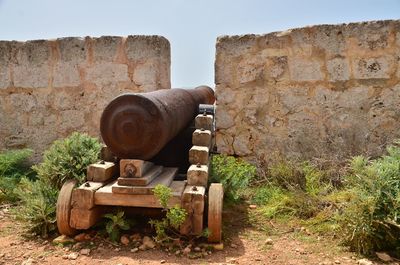 Old rusty wheel on field against wall