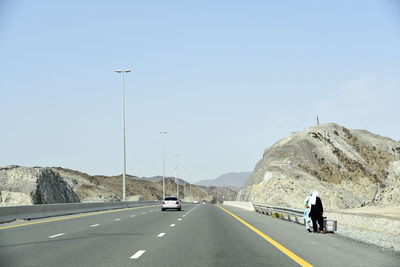 Vehicles on road against clear sky