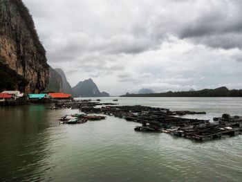 Boats in sea against cloudy sky