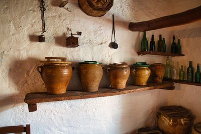 Earthenware and bottles shelf against wall