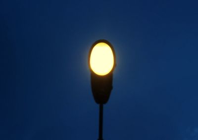 Low angle view of illuminated lamp against blue sky