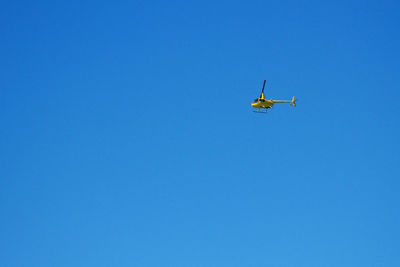 Low angle view of airplane flying against clear blue sky