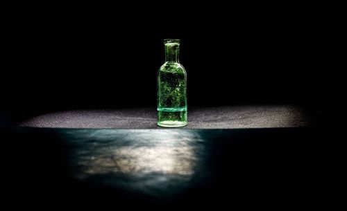 Close-up of bottle on table against black background