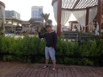 Full length portrait of man standing by building in city