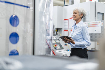 Smiling senior businesswoman using tablet in a factory