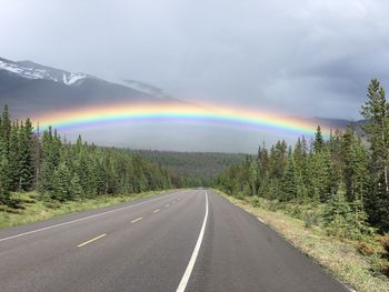 Rainbow over road against sky