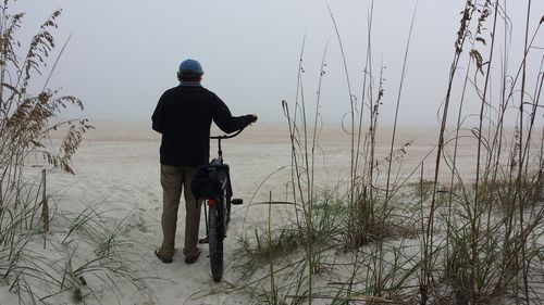 Rear view of man with bicycle at beach
