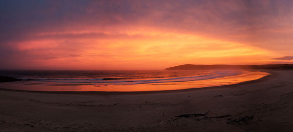 Scenic view of beach against sky at sunset