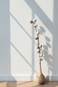 Close-up of white flower vase on table against wall at home